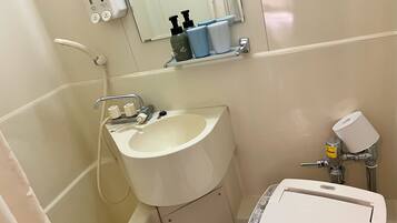 Un baño con lavamanos, espejo, dispensador de jabón e inodoro.