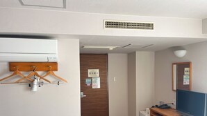 A hotel room with a wooden desk, a computer, a mirror, a clothes rack, and a door with a bulletin board. - Hotel Kurume Hills (Kurume)