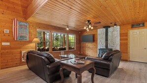 A cozy cabin interior with wooden walls, a stone fireplace, leather sofas, and a dining table. - 30 Min to Jackson Hole • Alpine Retreat • Hot Tub • Sleeps 12 (Alpine)