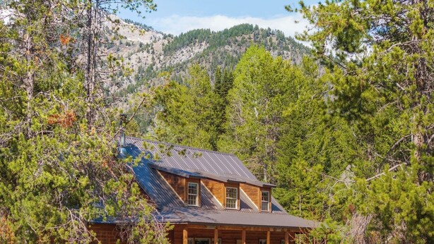 A wooden cabin with a balcony, surrounded by trees and mountains. - 30 Min to Jackson Hole • Alpine Retreat • Hot Tub • Sleeps 12 (Alpine)