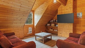 A cozy wooden cabin interior with a loft bed, a small table, and two red armchairs. - 30 Min to Jackson Hole • Alpine Retreat • Hot Tub • Sleeps 12 (Alpine)