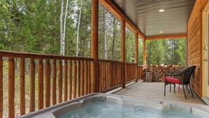 A wooden deck with a hot tub, chairs, and a stack of firewood. - 30 Min to Jackson Hole • Alpine Retreat • Hot Tub • Sleeps 12 (Alpine)