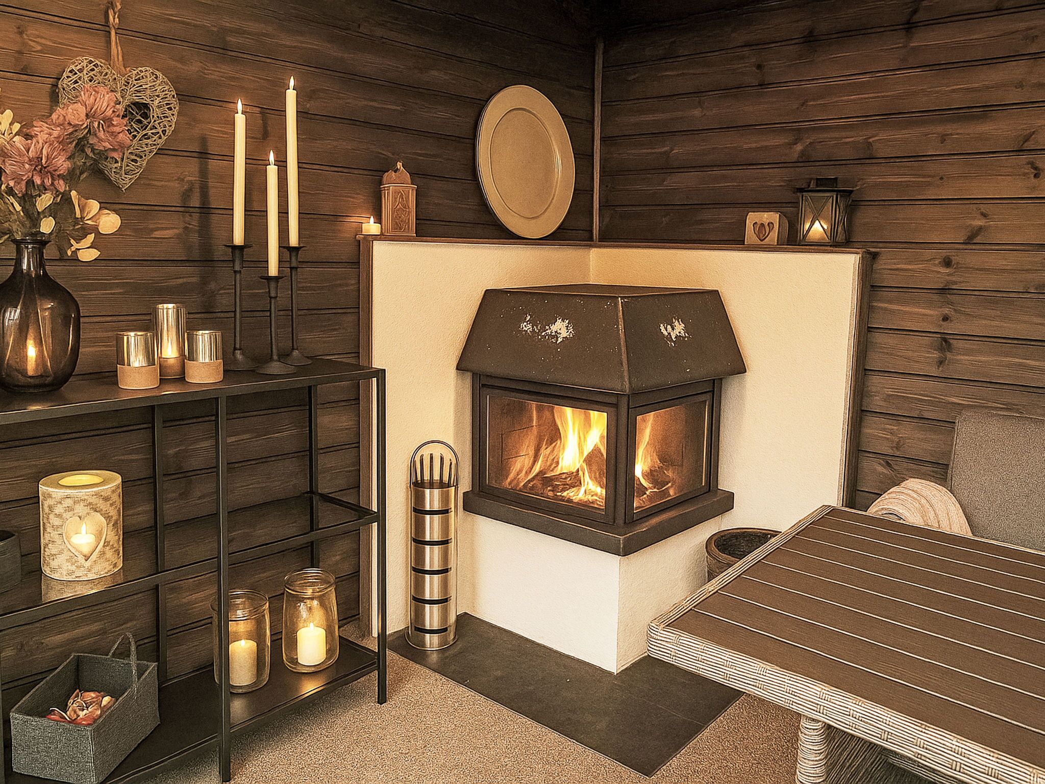 A cozy room with a fireplace, a table, and a shelf with candles and decorative items.