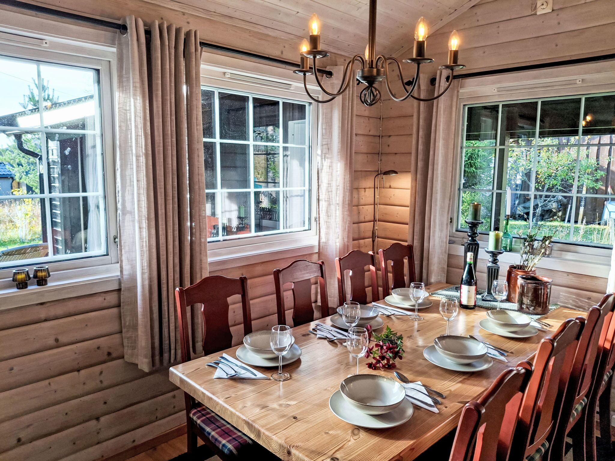 A dining area with a wooden table set for four, surrounded by wooden chairs.
