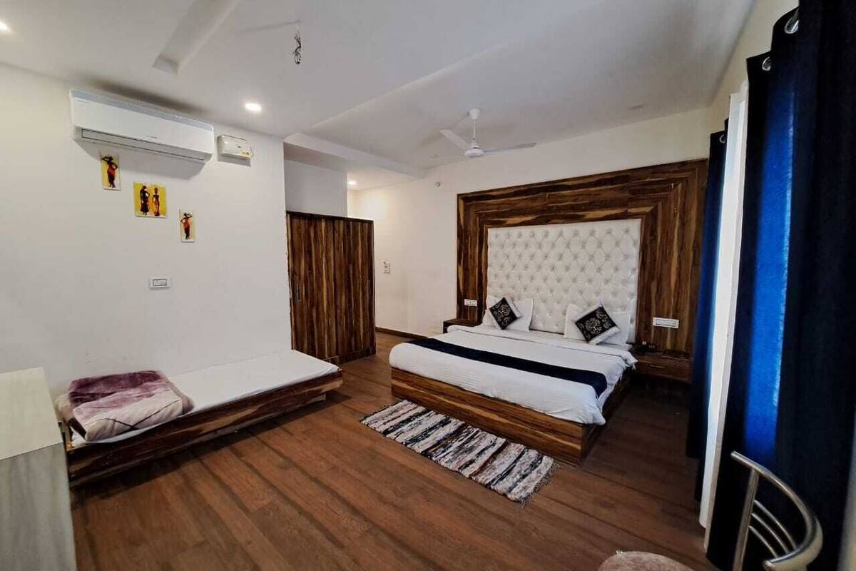 Ein Schlafzimmer mit einem Bett, einer kleinen Couch, Holzboden, einem Deckenventilator und einer Klimaanlage.