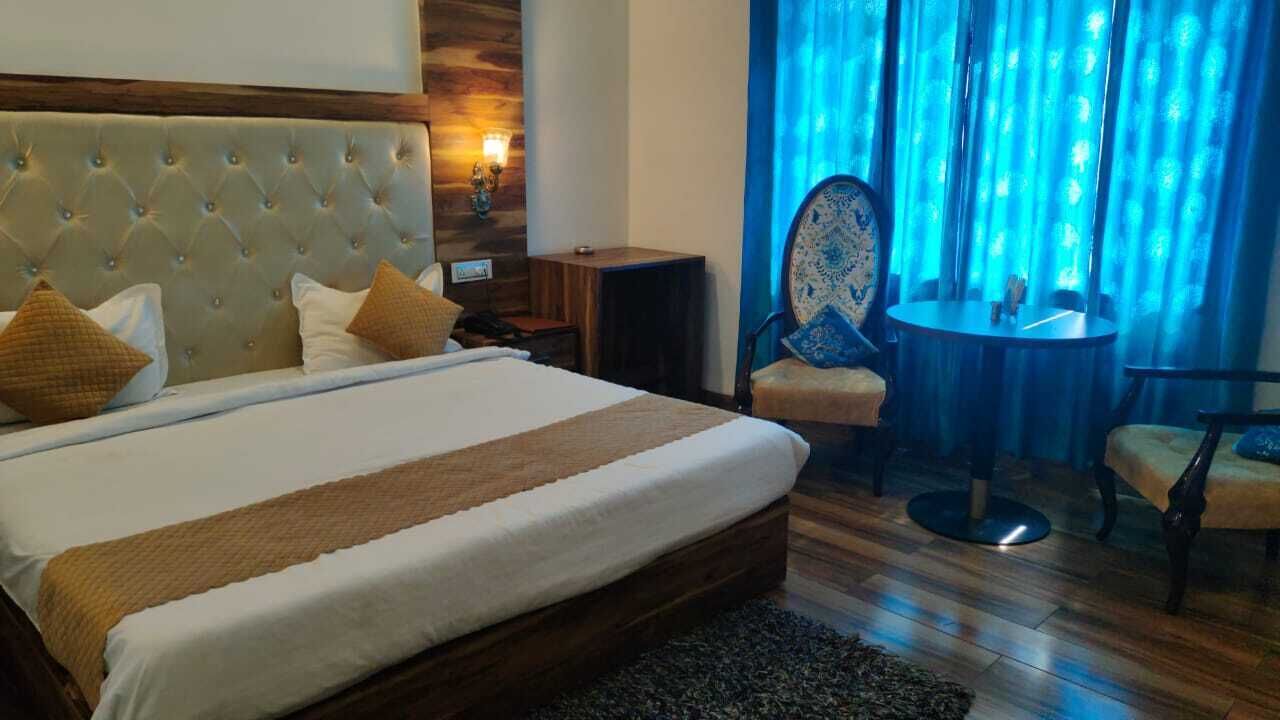A hotel room with a large bed, a wooden headboard, a small table, and a chair.
