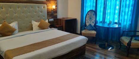 A hotel room with a large bed, a wooden headboard, a small table, and a chair.