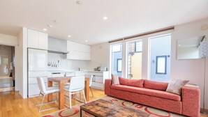 A modern living room with a red sofa, a wooden coffee table, and a dining area with white chairs. - Hangetsu Niseko (Kutchan)