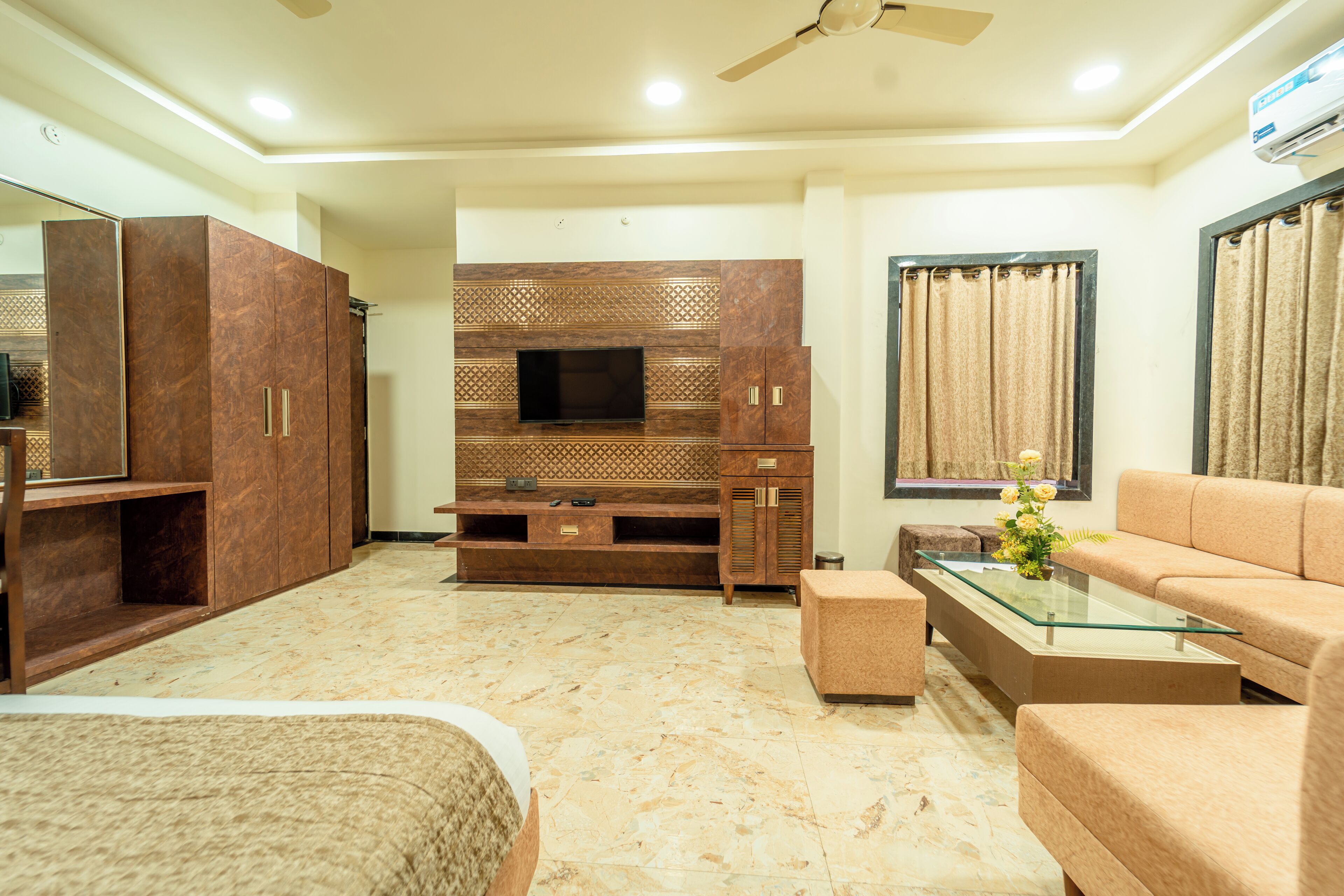 A modern living room with a flat-screen TV, a sofa, a glass coffee table, and a TV stand with cabinets.