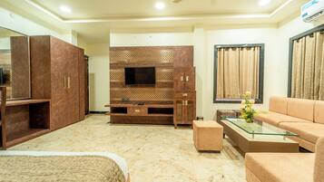 A modern living room with a flat-screen TV, a sofa, a glass coffee table, and a TV stand with cabinets.