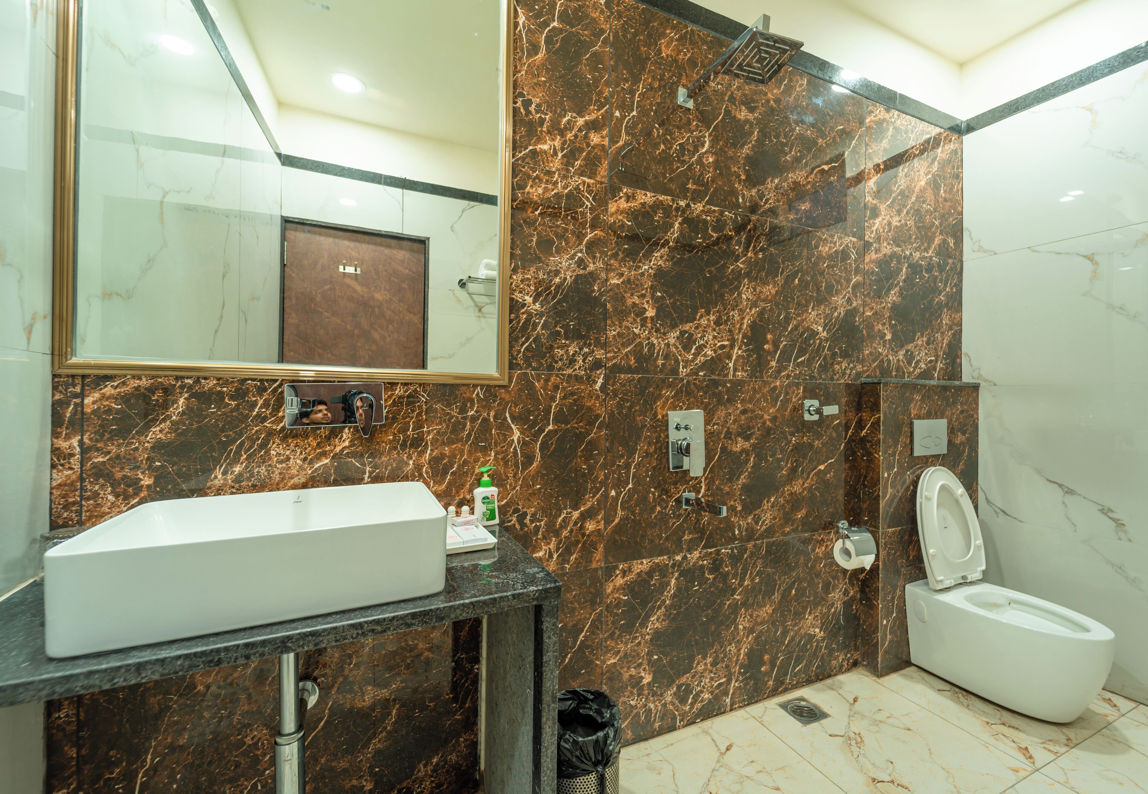 A bathroom with a marble sink, a toilet, and a mirror.