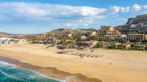 Un complejo turístico frente al mar con villas privadas, una playa de arena y vistas al océano.