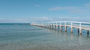 A long white pier extending into calm blue waters.