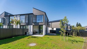Een modern herenhuis met twee verdiepingen, een ruime voortuin, een zichtbare garage en een schotelantenne.