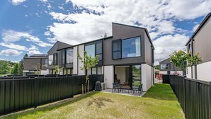 A modern two-story house with a covered patio, a fenced backyard, and a clear sky. - Ruru Retreat (Wanaka)