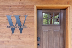 Uma porta de madeira com uma grande placa de metal com a inscrição 'WHISKEYSPRINGS' e uma janela acima.