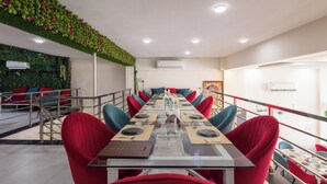 A conference room with a long table, red chairs, and a green wall with plants. - Hotel Pravasa Stay, Dewas Naka (Indore)