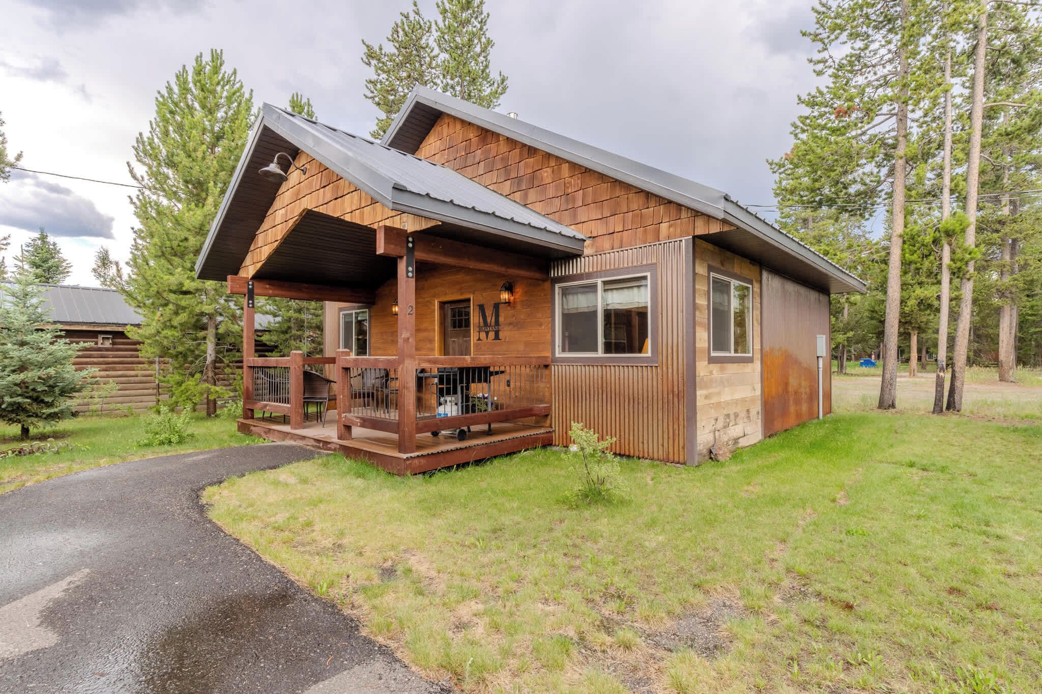 A log cabin with a porch, a visible door, and a small attached structure.