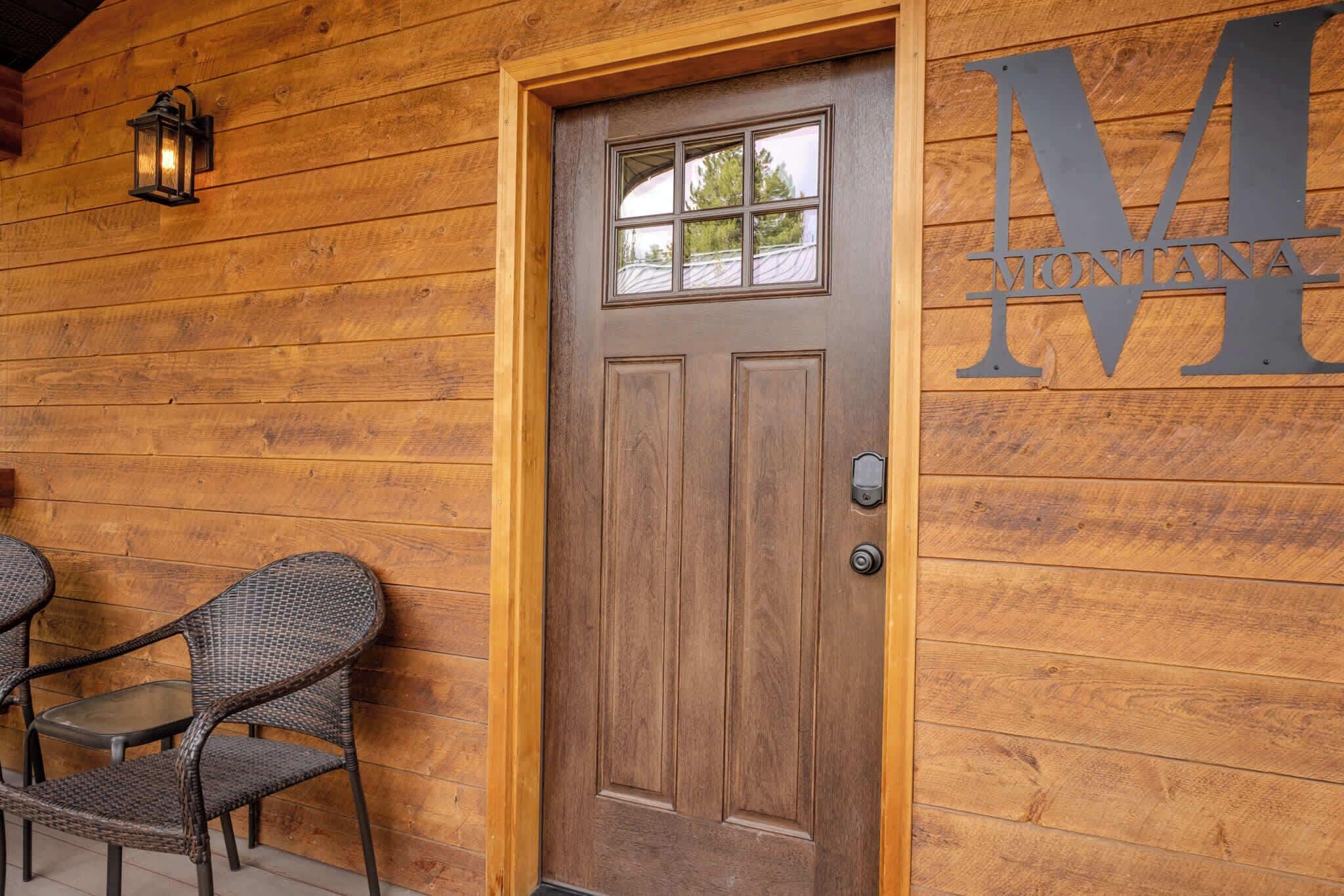 A wooden door with a glass panel and a metal sign with the letter 'M' on a wooden wall.