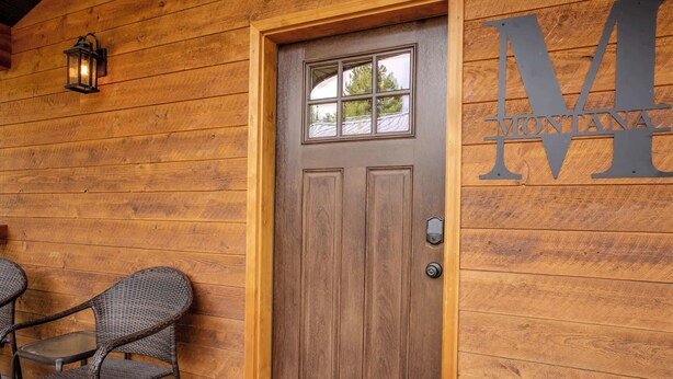 A wooden door with a glass panel and a metal sign with the letter 'M' on a wooden wall.