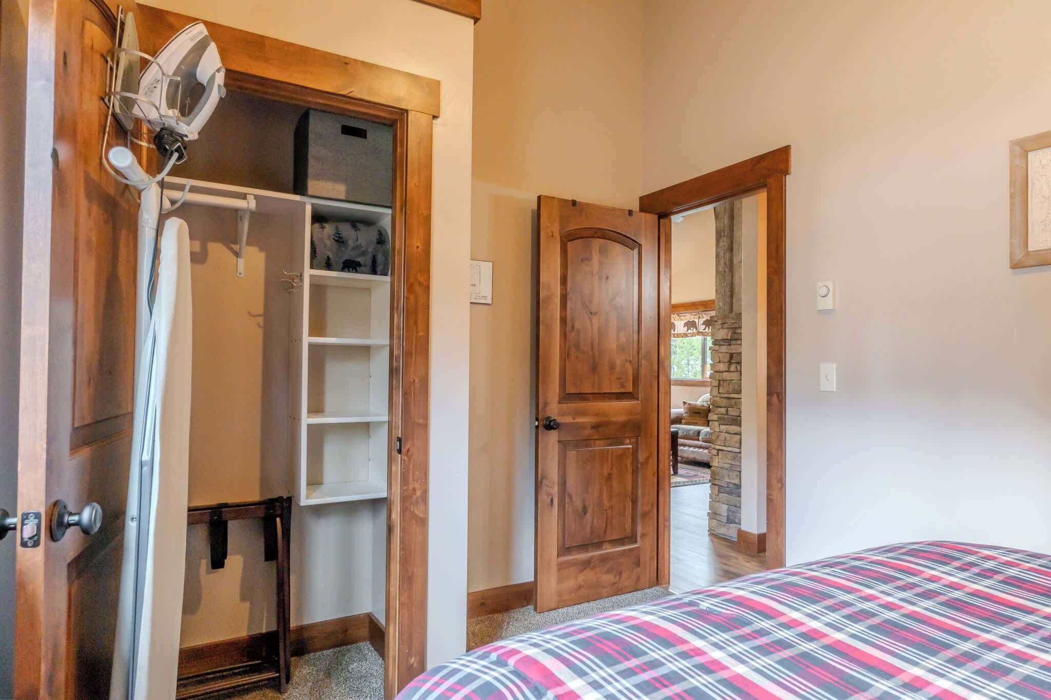 Ein Schlafzimmer mit einem Bett, einer Holztür, einem Schrank mit Regalen und einem Kleiderständer.
