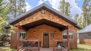 A wooden cabin with a porch, a door, and a small attached structure.
