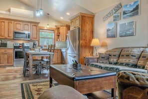 Una cocina con armarios de madera, un refrigerador y una zona de comedor con mesa y sillas.