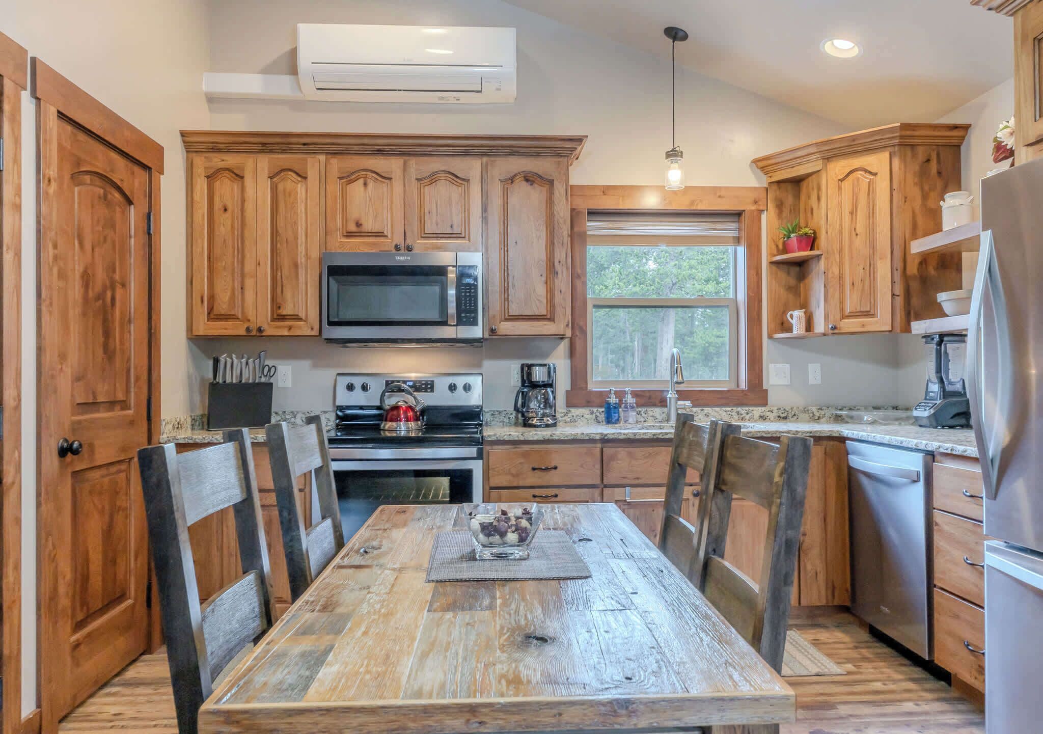 A kitchen with wooden cabinets, a stainless steel refrigerator, a microwave, and a stove.