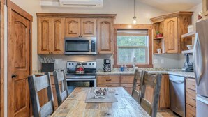 A kitchen with wooden cabinets, a stainless steel refrigerator, a microwave, and a stove.