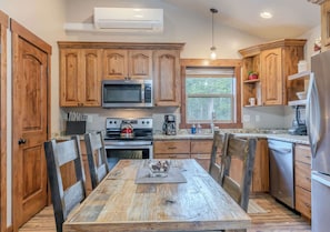 A kitchen with wooden cabinets, a stainless steel refrigerator, a microwave, and a stove. - Montana Cabin Summary (West Yellowstone)
