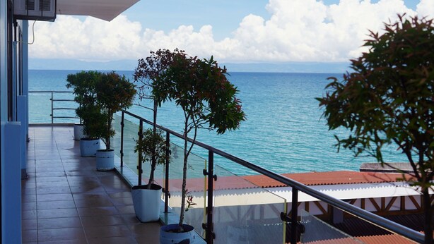 A balcony with potted plants, a railing, and a view of the sea. - Hidden Valley Beach Resort (Pinamungajan)