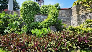 A garden with a rock wall, a water tower, and a sign reading "IDEN VALLE BEACH". - Hidden Valley Beach Resort (Pinamungajan)