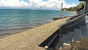 A pebble beach with a staircase leading down to the water, a clear sky, and distant mountains. - Hidden Valley Beach Resort (Pinamungajan)
