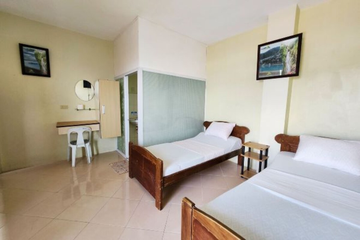 A room with two beds, a desk, a chair, and a mirror.