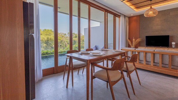 A modern dining area with a large table, chairs, and a television. - Villa Taman Famindo Canggu V-8 (Canggu)
