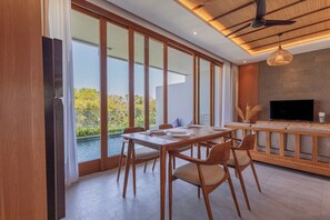 A modern dining area with a large table, chairs, and a television. - Villa Taman Famindo Canggu V-8 (Canggu)