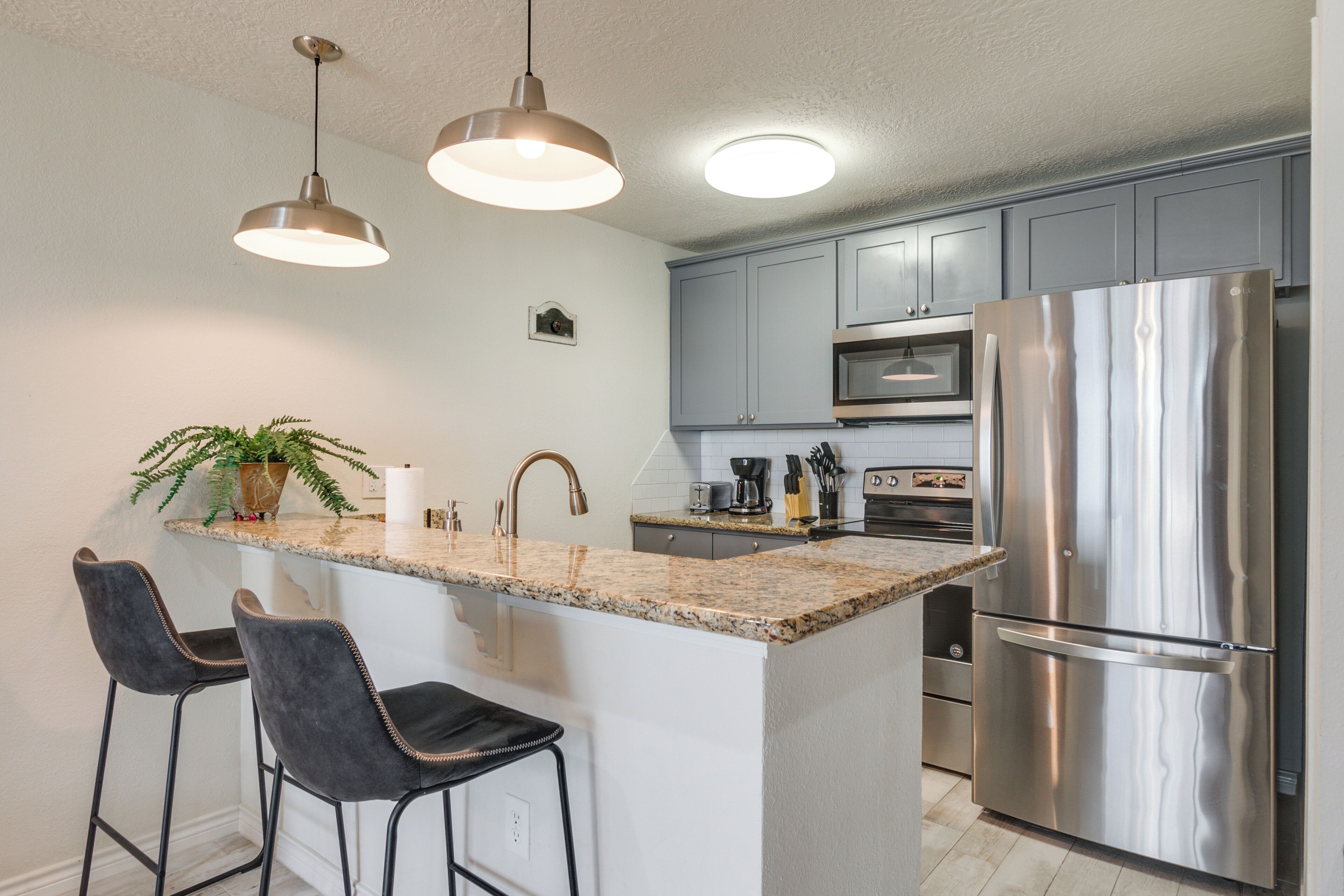 A modern kitchen with granite countertops, stainless steel appliances, and pendant lighting.