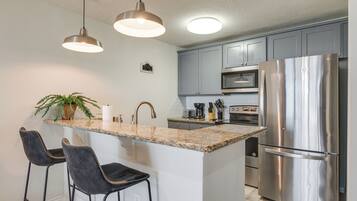 A modern kitchen with granite countertops, stainless steel appliances, and pendant lighting.