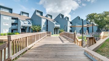 A wooden boardwalk leading to a row of blue apartment buildings with balconies and a clear sky.