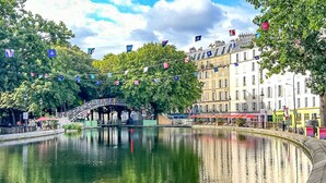 A riverside view with a bridge, buildings, and flags. - Mark 22 - Large studio Canal Saint-Martin views (Paris)