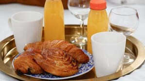 Aamiaistarjotin, jossa on croissantteja, appelsiinimehua ja valkoviinilaseja.
