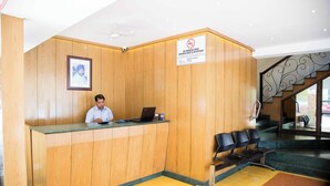 A reception desk with a no-smoking sign, a framed picture on the wall, and a staircase with a railing. - Hotel Aroma Executive (Panaji)