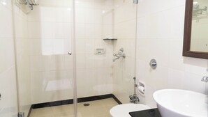 A modern bathroom with a glass-enclosed shower, a white sink, and a toilet. - Hotel Aroma Executive (Panaji)