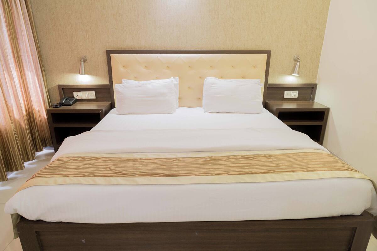 A hotel room with a large bed, two bedside tables, and a headboard.
