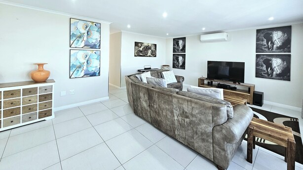 A modern living room with a grey sofa, a TV, and artwork on the walls. - Portmarnock House (Cape Town)