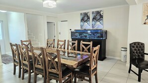 A dining area with a wooden table and chairs, a fish tank, and a television. - Portmarnock House (Cape Town)