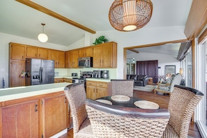 A spacious kitchen with wooden cabinets, a refrigerator, and a microwave. There is a dining area with wicker chairs and a table. - Mt. Nebo Oasis in La Mesa w/ Wraparound Deck (La Mesa)