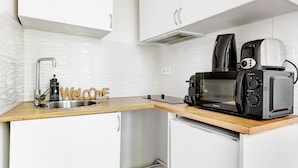 A compact kitchenette with a stainless steel sink, a black toaster oven, and a coffee maker. - TBS 23 - Pretty suite in Canal Saint-Martin area (Paris)