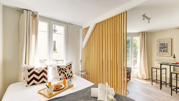 A hotel room with a bed, breakfast tray, towels, and a view of the outside. - TBS 23 - Pretty suite in Canal Saint-Martin area (Paris)