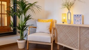 A cozy room with a wooden chair, a potted plant, a white cabinet with a lattice design, and a framed book on the cabinet. - Tropical Wellness Suite Sauna, whirlpool, TV, BBQ (Büdesheim)